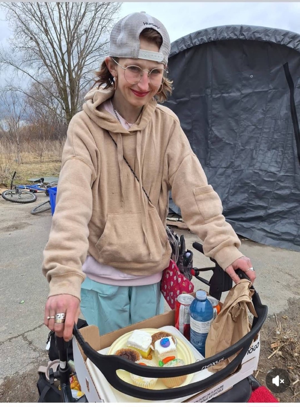 A volunteer wheels a cart stacked with packed meals, drinks and desserts out to the tents at Belle Park